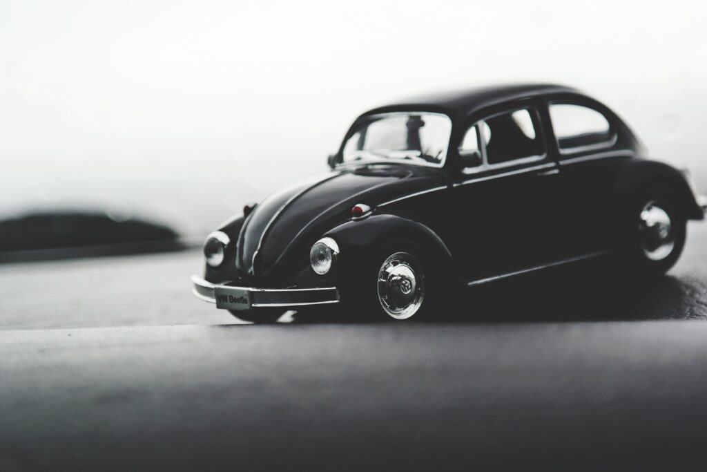 A close-up shot of a classic Volkswagen Beetle toy car on a smooth surface with soft lighting.